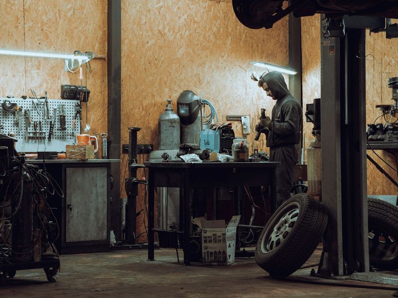 Auto repair shop owner reviewing a diagnostic scan with a technician beside a vehicle on a lift